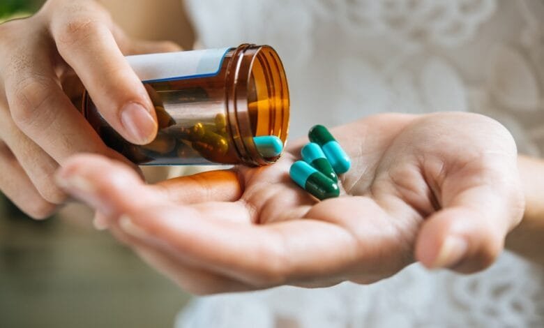 moteris deda vitaminus į delną